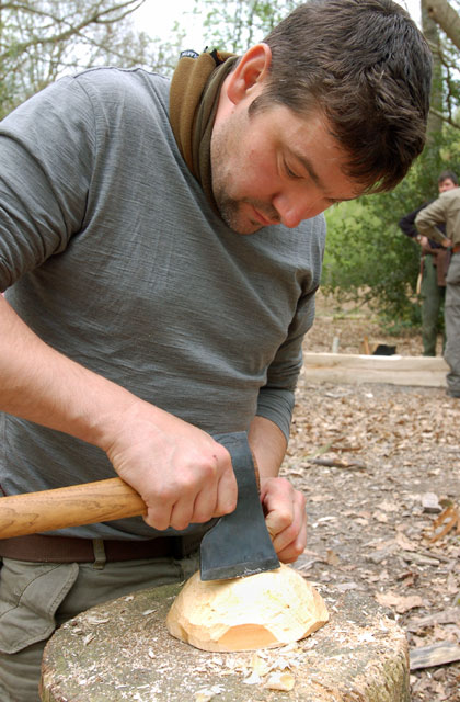 One of the students shaping the outside of a bowl with his axe