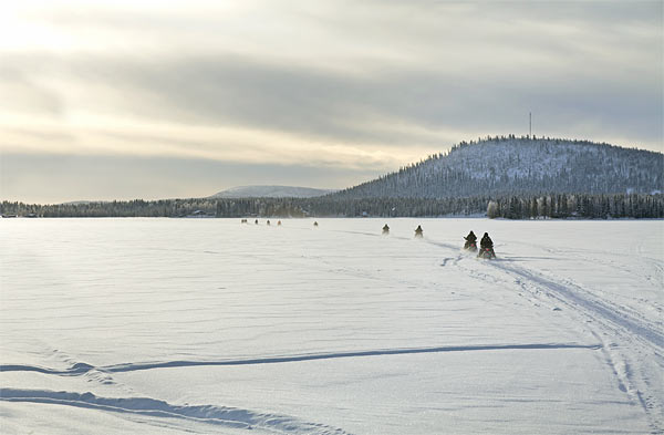 The group traversing the Arctic wilderness by snowmobile
